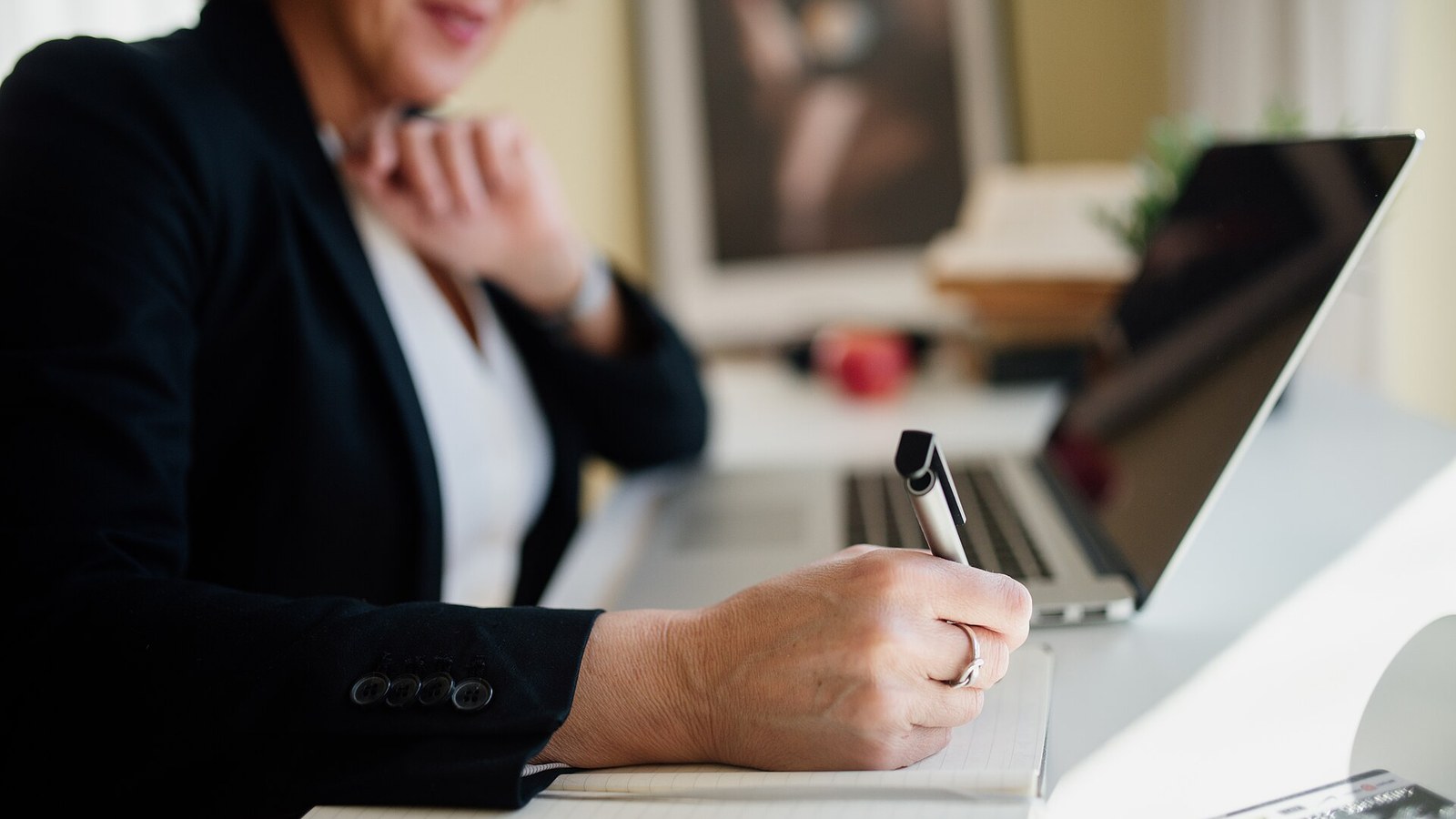 A professional taking notes during a meeting at an office desk