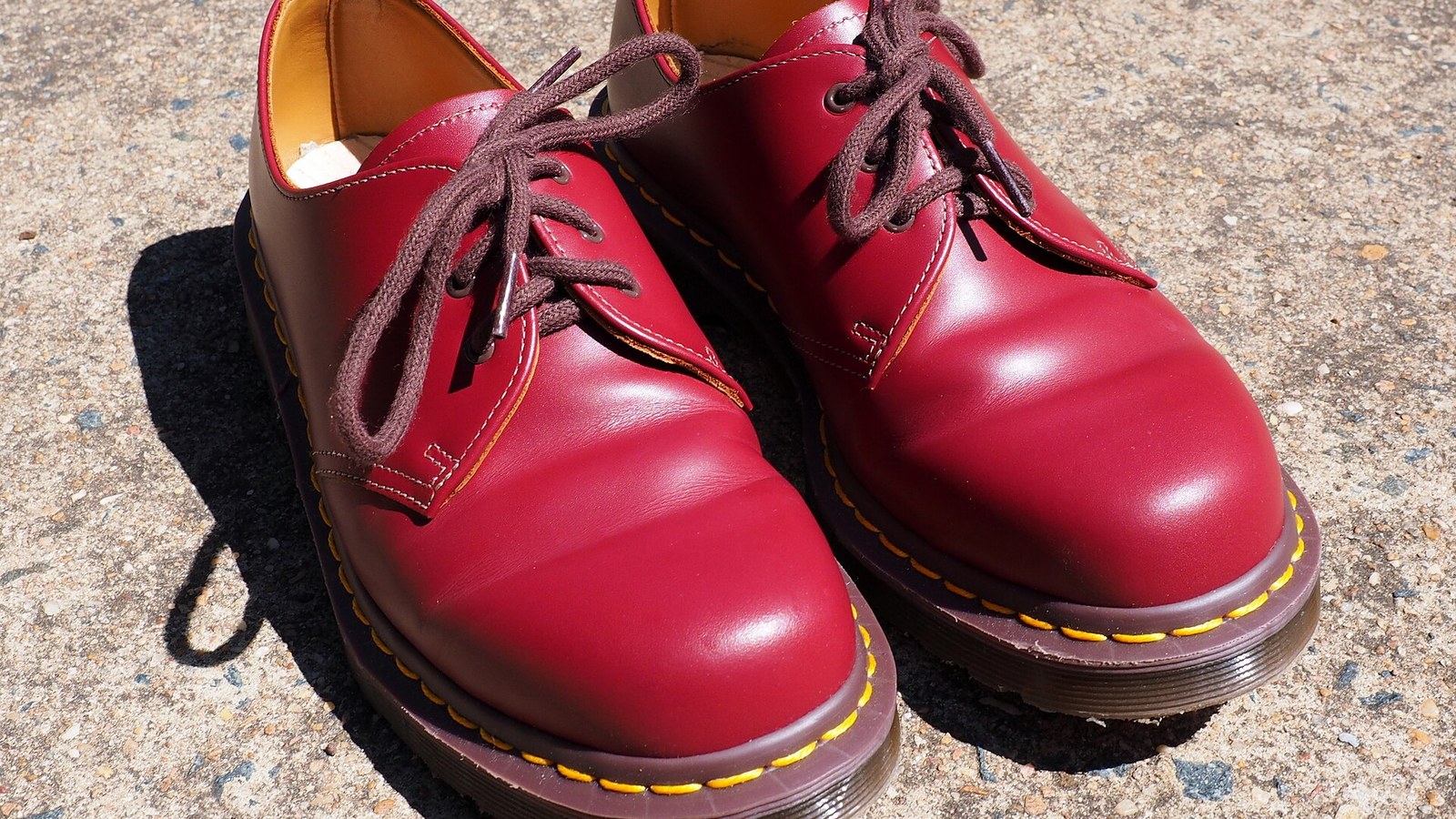 A pair of cherry red Dr. Martens 1461 shoes in sunlight