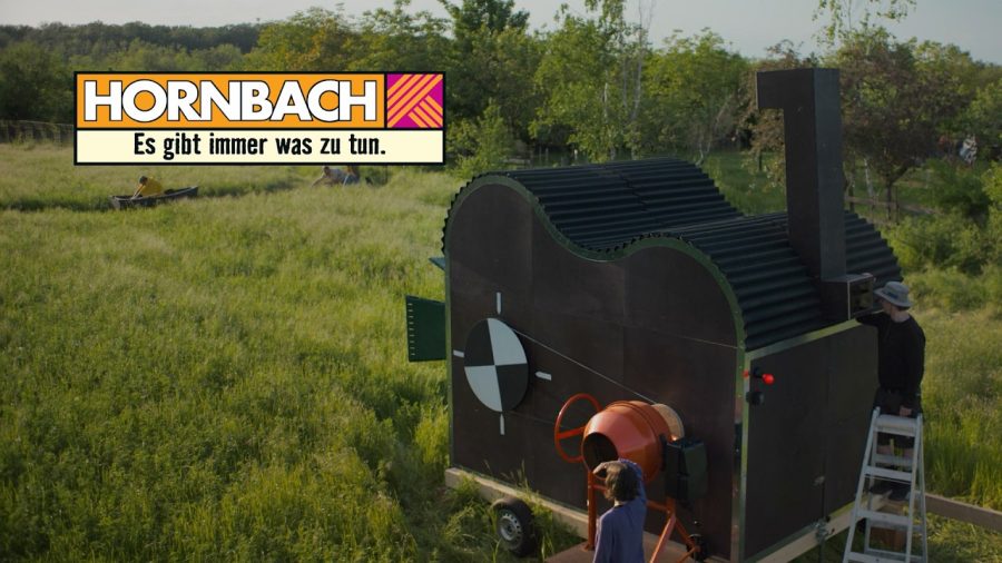 The van-sized 35mm film camera Hornbach built from DIY products, in a field with its crew
