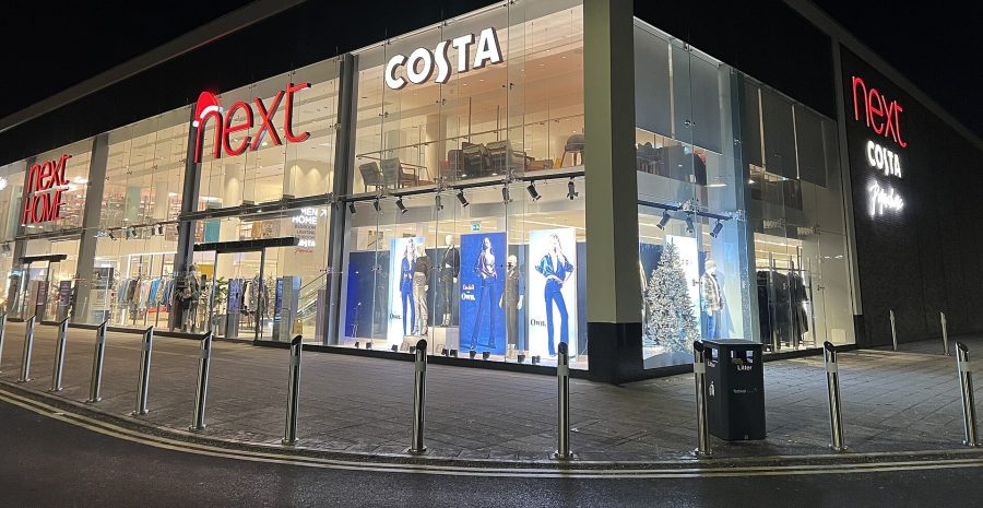 A Next and Next Home store lit up at night