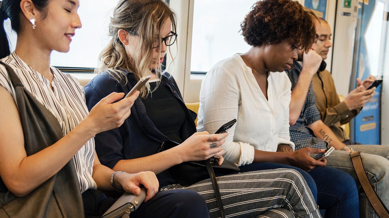 Commuters looking at their smartphones on a train