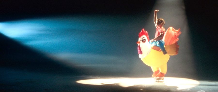 A figure skater in an inflatable chicken costume under a spotlight in Three's Let Fun In advert
