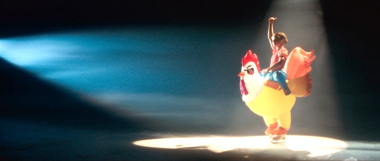 A figure skater in an inflatable chicken costume under a spotlight in Three's Let Fun In advert