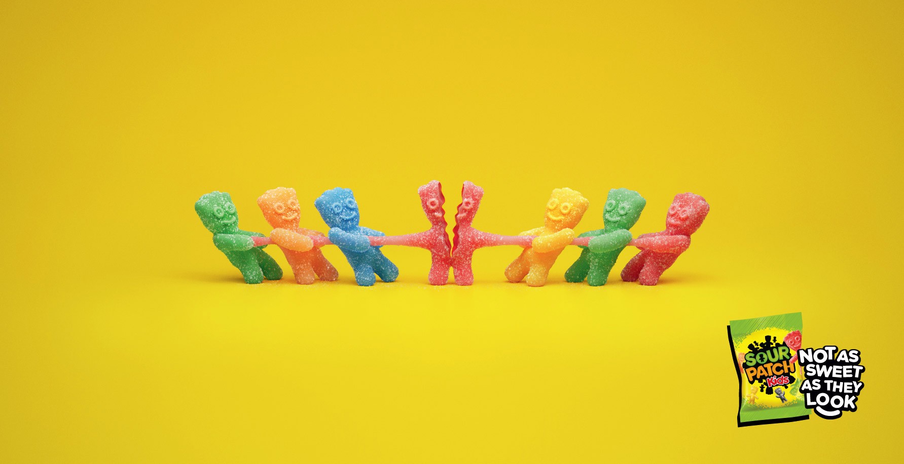 Sour Patch Kids poster showing the sweets pulling one apart in a tug of war